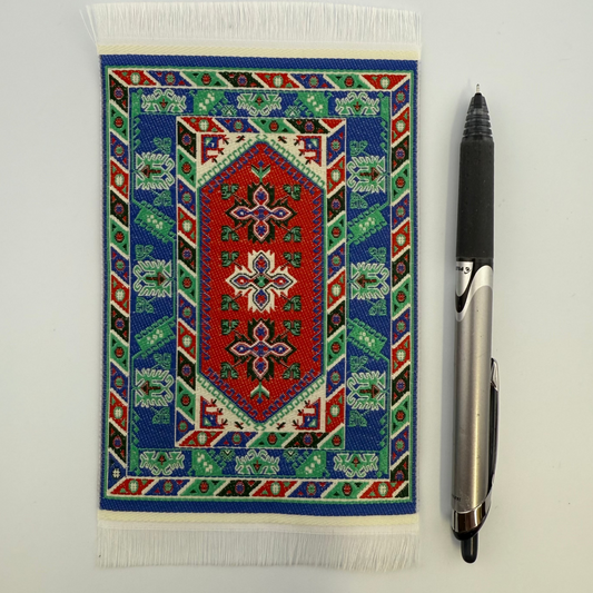 Decorative rug with geometric pattern next to a pen on a white surface