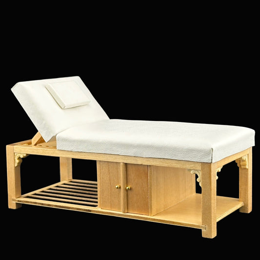 Wooden massage table with white cushion on a dark background